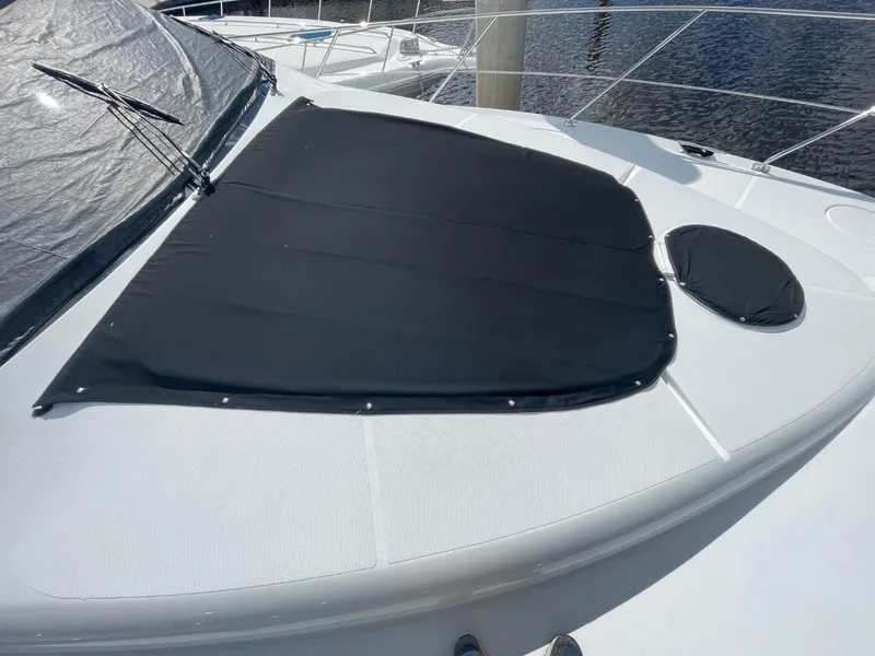 Slide: The Image of 1998 Carver 530 Voyager Pilothouse yacht deck with black cover, docked by water. - 11