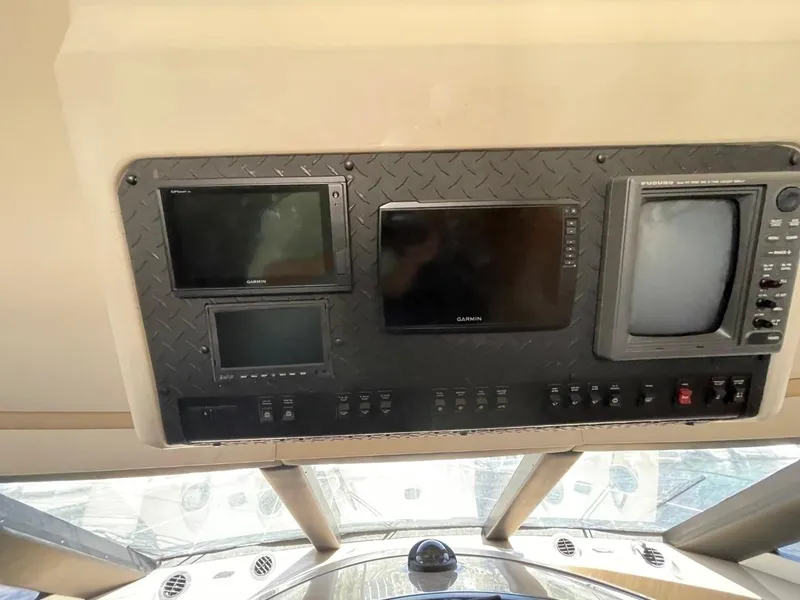 Slide: The Image of Control panel of a 1998 Carver 530 Voyager Pilothouse with multiple screens and switches. - 21