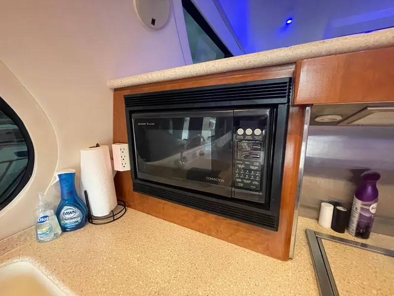 Slide: The Image of Microwave in 1998 Carver 530 Voyager Pilothouse kitchen with cleaning supplies nearby. - 39