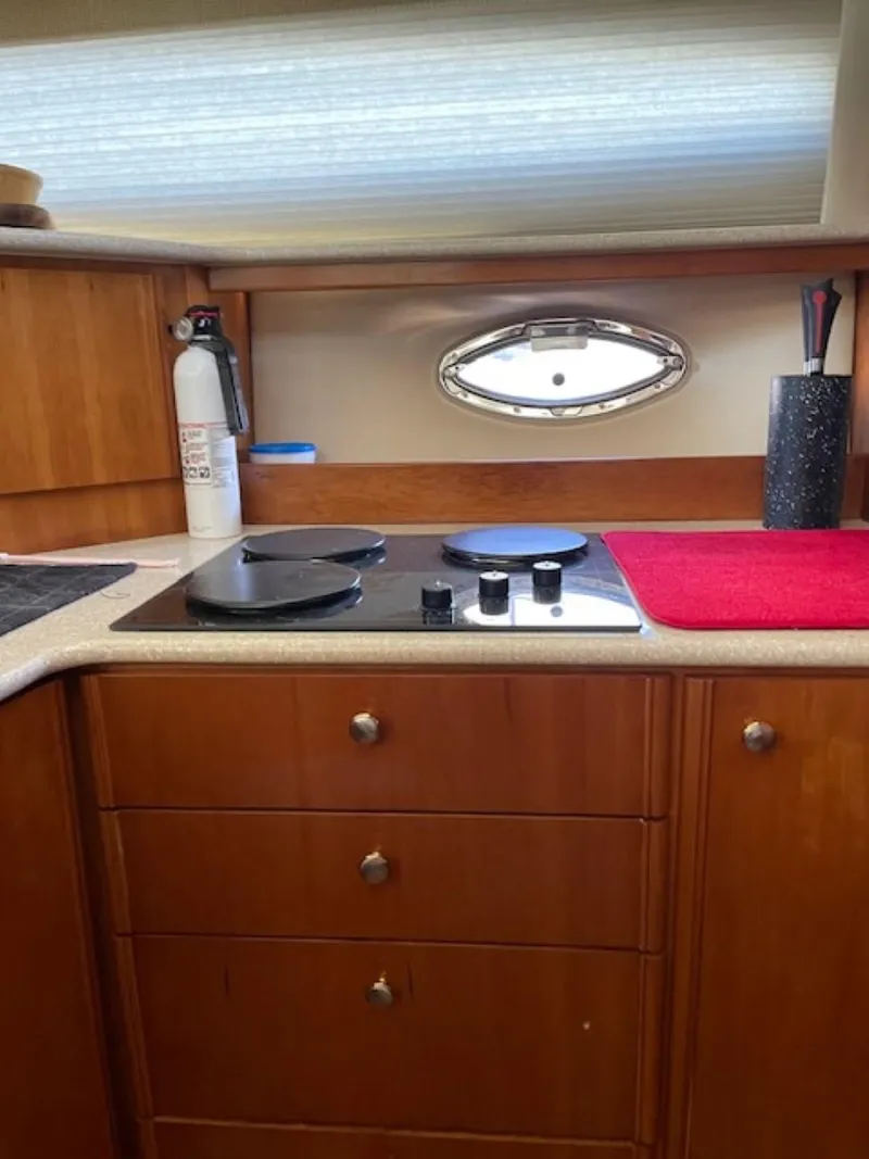 Slide: The Image of 2004 Meridian 459 Motoryacht kitchen with stove, wooden cabinets, and porthole window. - 37