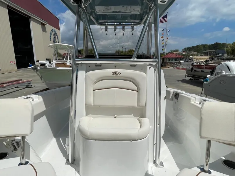 Slide: The Image of 2022 Sea Hunt 234 Ultra boat interior with seating and T-top in a marina setting. - 35