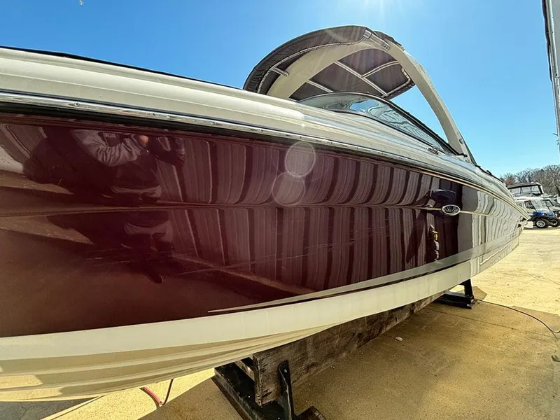 Slide: The Image of 2013 Sea Ray 250 SLX boat with maroon hull, docked under clear blue sky. - 6