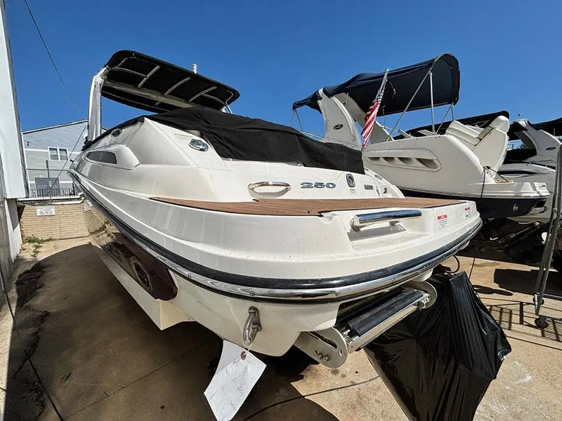 Slide: The Image of 2013 Sea Ray 250 SLX boat with cover, docked outdoors under clear blue sky. - 7