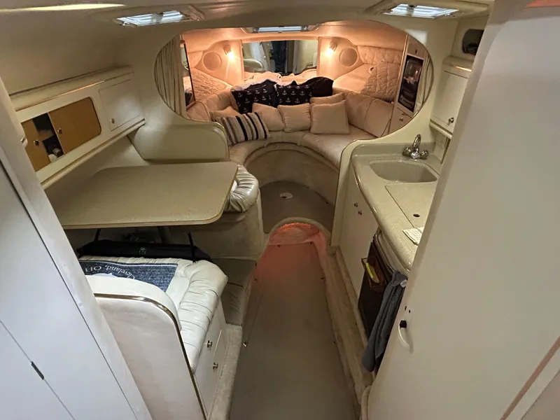 Slide: The Image of Interior of a 2000 Sea Ray 290 Sundancer boat, featuring cozy seating and compact kitchen area. - 27