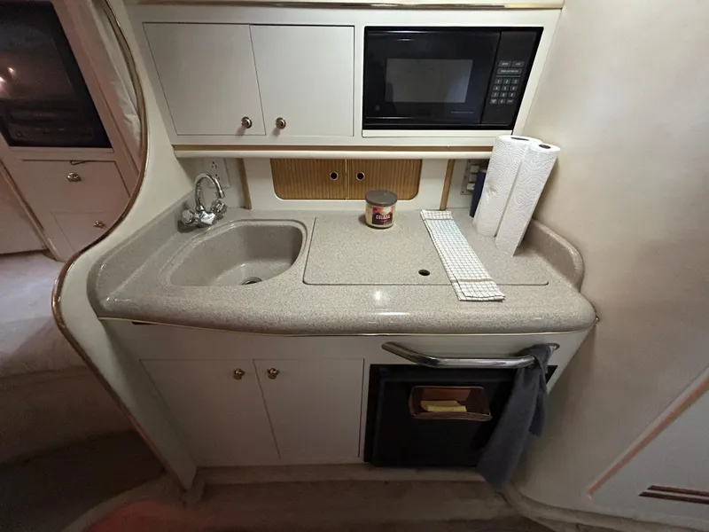 Slide: The Image of 2000 Sea Ray 290 Sundancer galley with sink, microwave, and storage cabinets. - 31