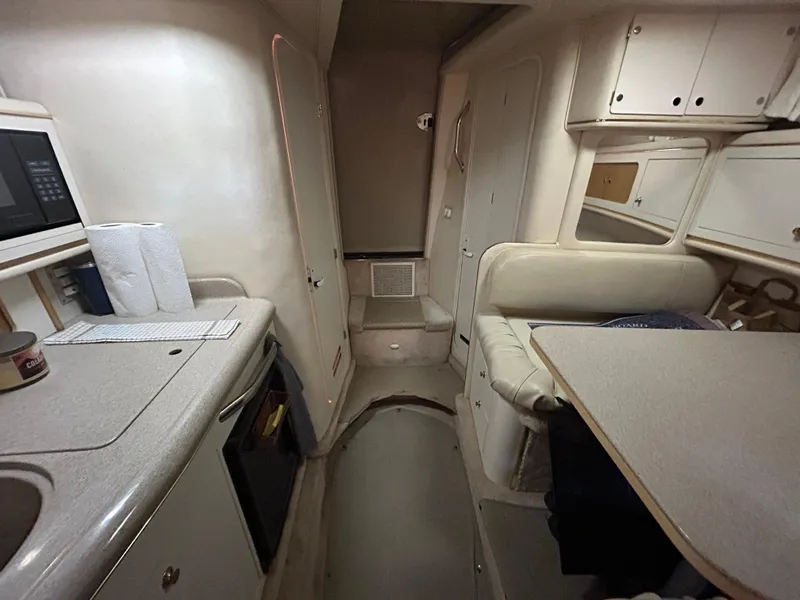 Slide: The Image of Interior of 2000 Sea Ray 290 Sundancer boat, featuring kitchenette and seating area. - 35