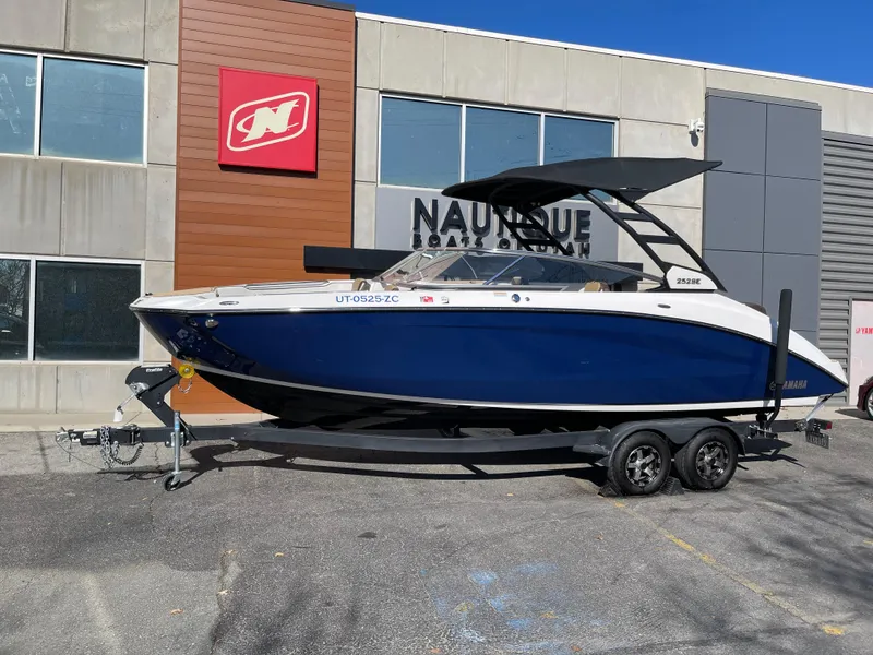 Slide: The Image of 2021 Yamaha Boats 252SE on trailer, parked outside a building with signage. - 0
