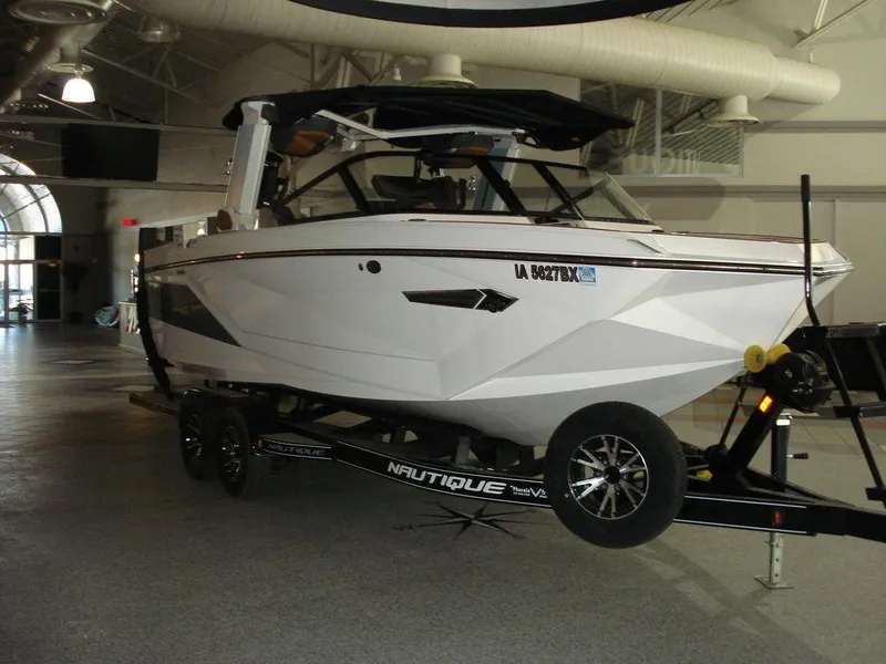 The Image of 2024 Nautique Super Air Nautique G23 boat on trailer in indoor showroom. - 1