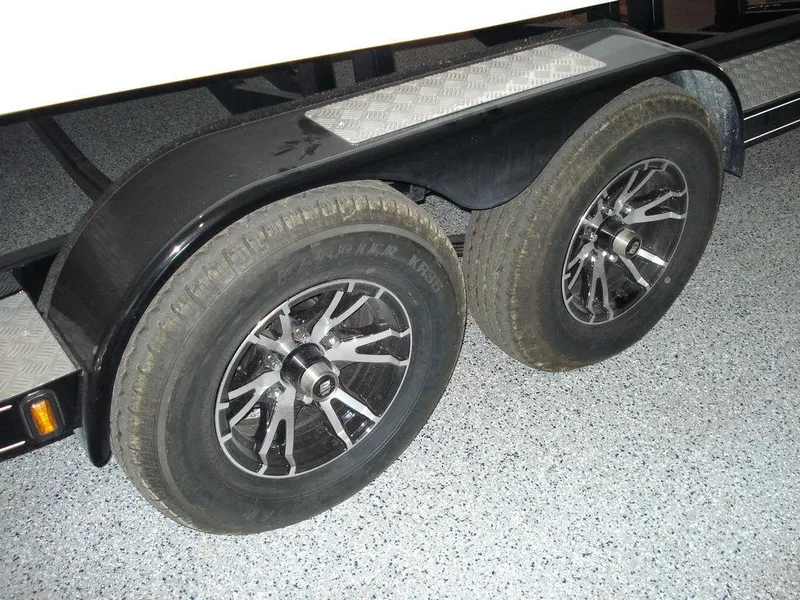 Slide: The Image of Trailer wheels of 2024 Nautique Super Air Nautique G23 boat on a textured floor. - 10