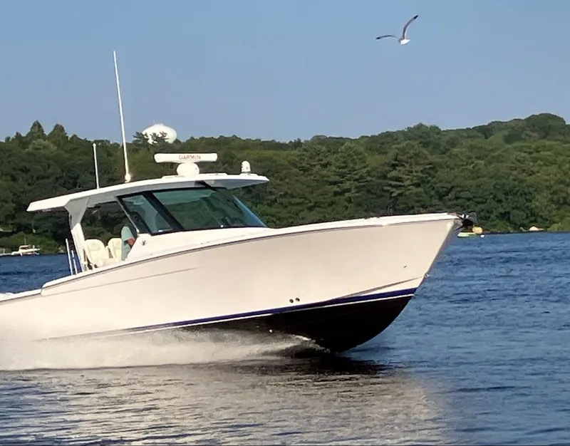 Slide: The Image of 2022 Bertram 39 CC boat cruising on a lake with scenic forest backdrop. - 0