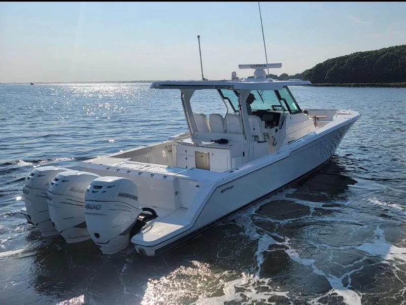 Slide: The Image of 2022 Bertram 39 CC boat on water, featuring twin outboard engines, under clear sky. - 1