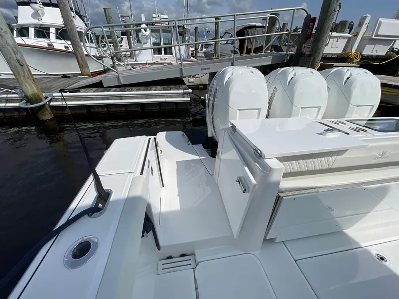 Slide: The Image of 2022 Bertram 39 CC boat docked, featuring triple outboard engines and sleek white deck design. - 19