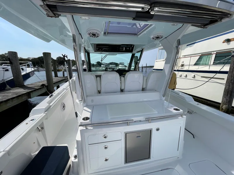 Slide: The Image of 2022 Bertram 39 CC boat interior with seating and storage, docked at a marina. - 24