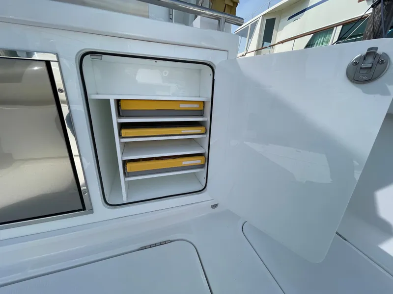 Slide: The Image of 2022 Bertram 39 CC boat storage compartment with yellow trays, open door. - 29