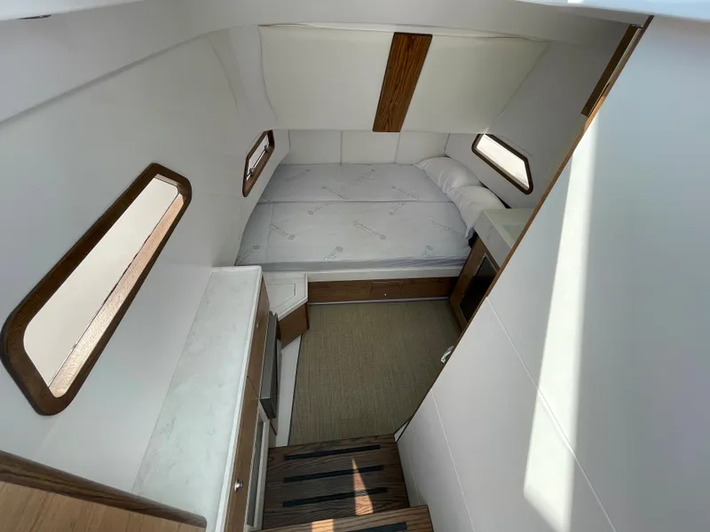 Slide: The Image of 2022 Bertram 39 CC cabin interior with bed, wooden accents, and windows. - 49