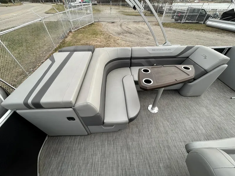 Slide: The Image of 2021 Bennington 21SLX boat interior with gray seating and table, featuring cup holders. - 15