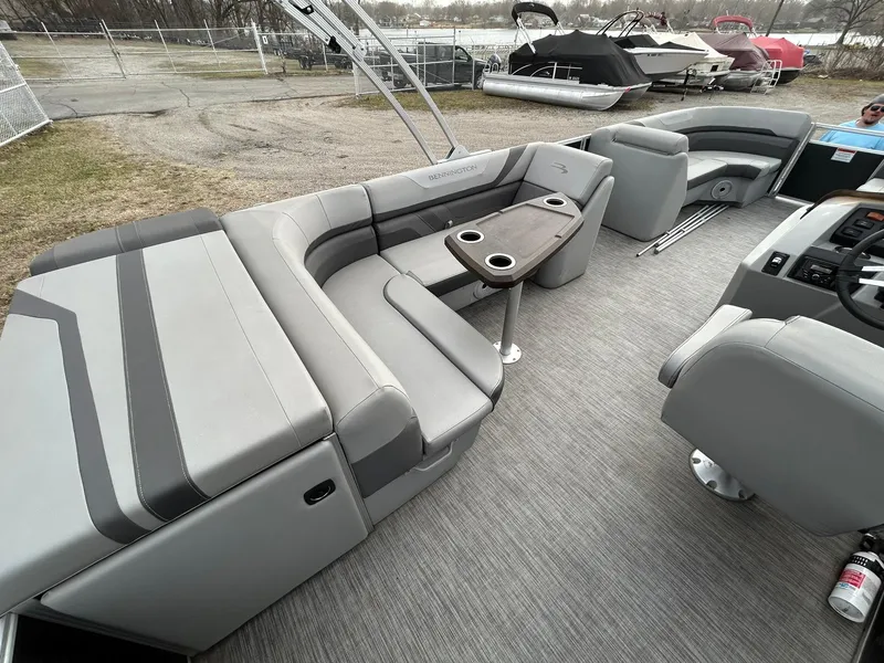 Slide: The Image of 2021 Bennington 21SLX pontoon boat interior with gray seating and table, docked near other boats. - 17