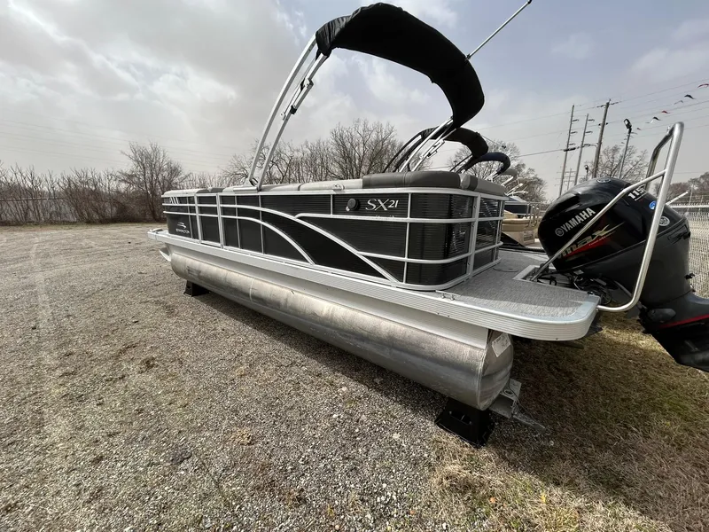 Slide: The Image of 2021 Bennington 21SLX pontoon boat with Yamaha outboard motor, parked on gravel. - 3