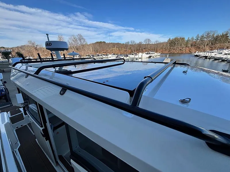Slide: The Image of Navan C30 boat roof with railing, docked by a serene river under a clear blue sky. - 45