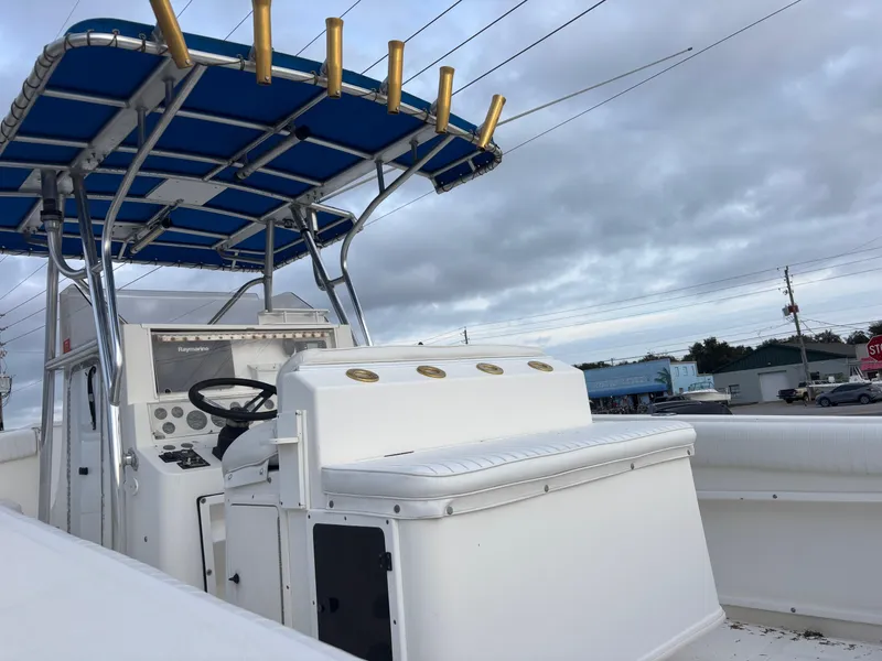 Slide: The Image of 1997 Jefferson Marlago 35 FS boat with blue canopy and white seating, docked under cloudy skies. - 16
