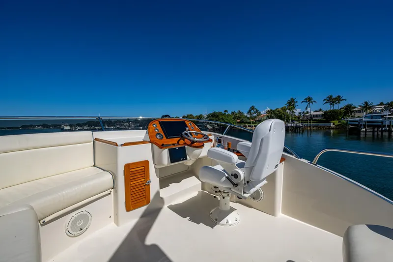 Slide: The Image of 2019 Hinckley Talaria 43 Flybridge helm with seating, overlooking serene waterfront and palm trees. - 14