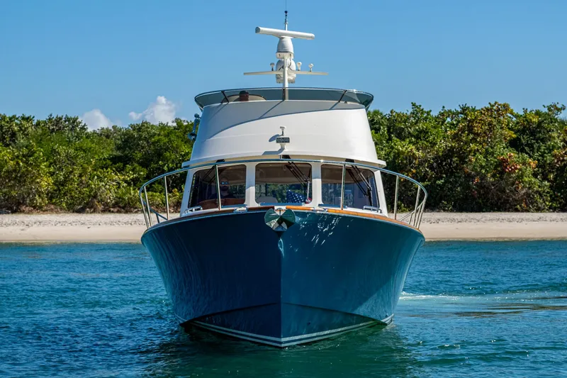 Slide: The Image of 2019 Hinckley Talaria 43 Flybridge yacht on clear water near a sandy beach. - 2
