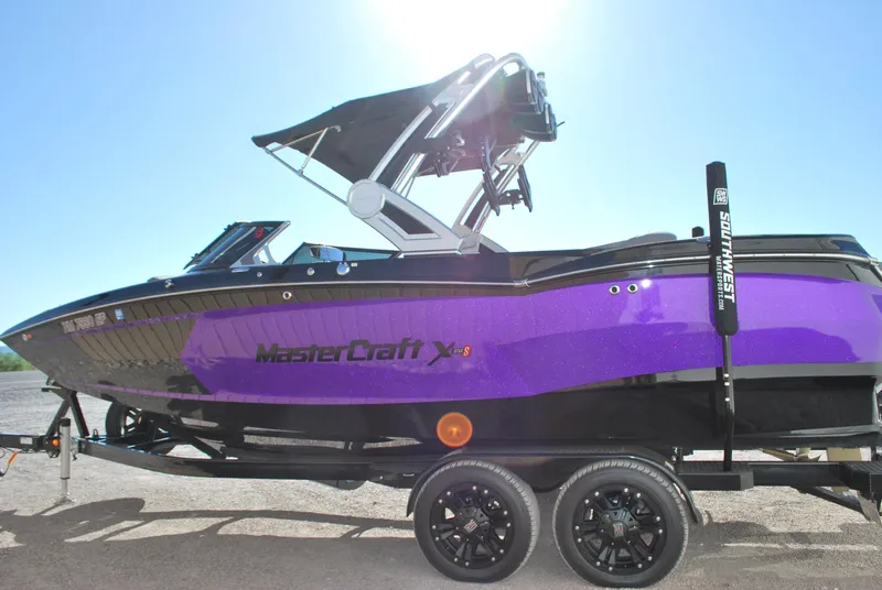Slide: The Image of 2023 MasterCraft XStar S boat with purple and black design on a trailer. - 2