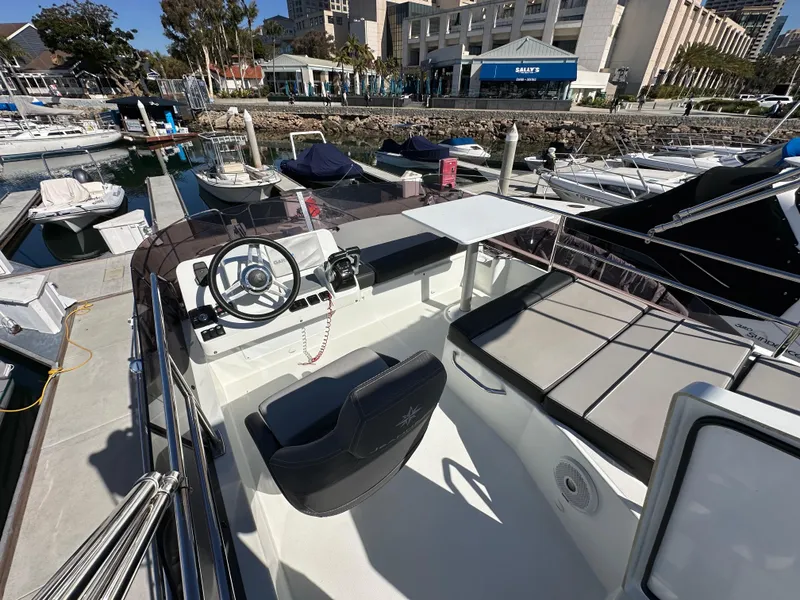 Slide: The Image of 2021 Jeanneau NC 1095 Flybridge boat at marina, featuring helm and seating area. - 14