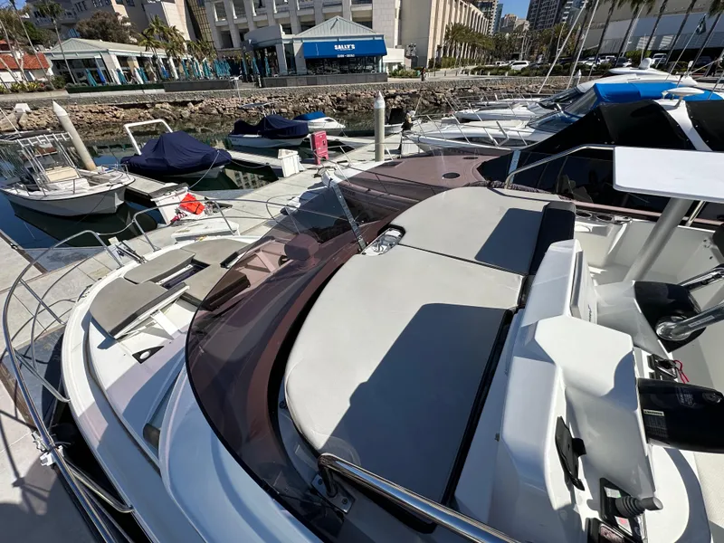 Slide: The Image of 2021 Jeanneau NC 1095 Fly yacht docked at marina, showcasing spacious deck and seating area. - 18