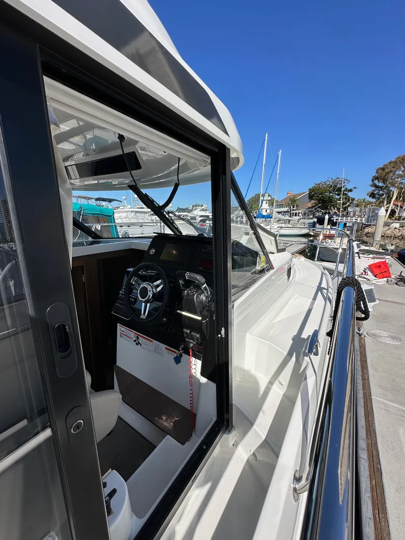 Slide: The Image of 2021 Jeanneau NC 1095 Fly yacht docked, showcasing helm and sleek design. - 28