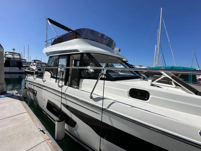 Slide: The Image of 2021 Jeanneau NC 1095 Fly yacht docked at marina under clear blue sky. - 5