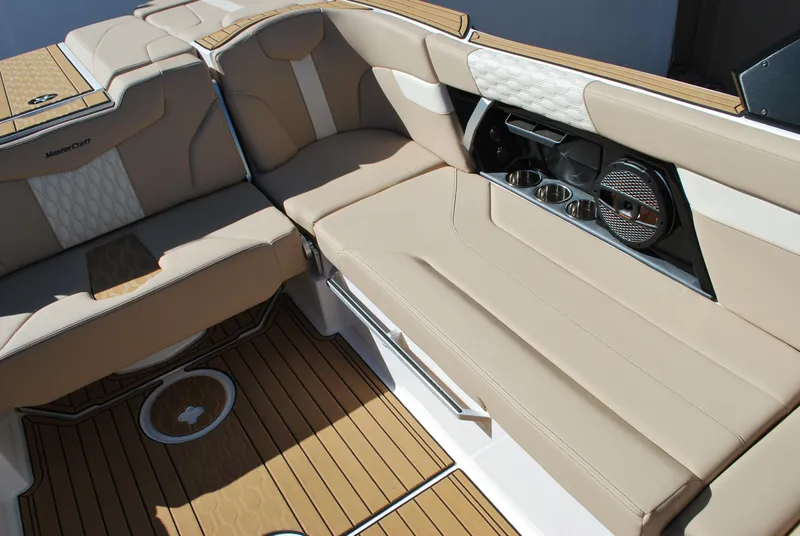 Slide: The Image of 2025 MasterCraft XT25 boat interior with beige seating and wood flooring. - 10