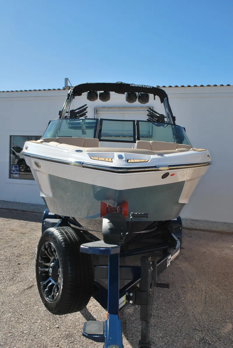 Slide: The Image of 2025 MasterCraft XT25 boat on trailer, front view, outdoors. - 2