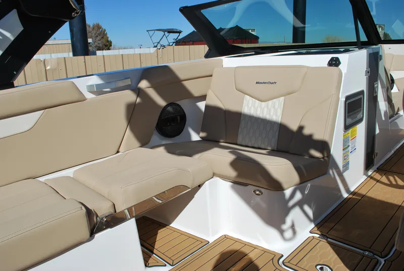 Slide: The Image of 2025 MasterCraft XT25 boat interior with beige seating and wood flooring. - 5