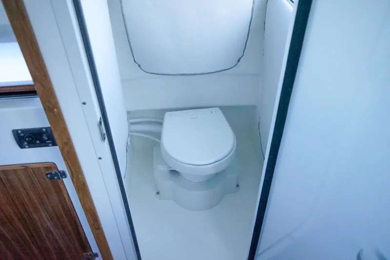 Slide: The Image of 2025 C-Dory 25' Tomcat Catamaran bathroom with compact marine toilet. - 12
