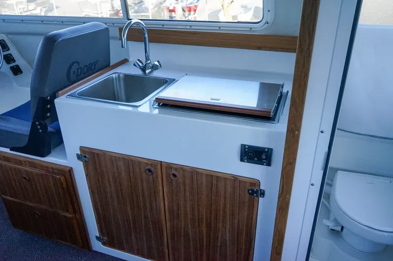 Slide: The Image of Interior of 2025 C-Dory 25' Tomcat Catamaran with sink, storage, and toilet. - 13