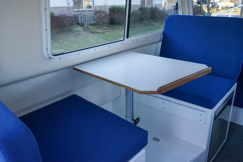 Slide: The Image of Interior of 2025 C-Dory 25' Tomcat Catamaran with blue seating and table. - 14
