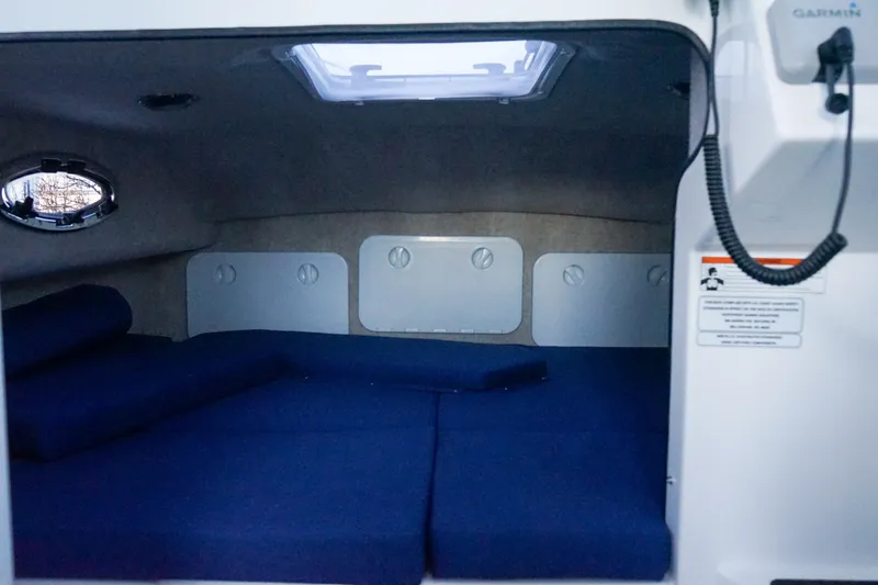 Slide: The Image of 2025 C-Dory 25' Tomcat Catamaran cabin interior with blue cushions and porthole. - 15