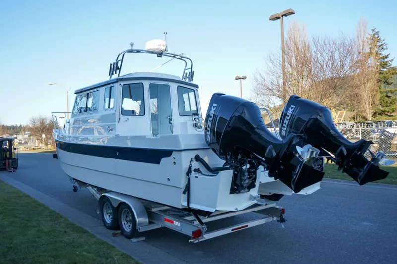 Slide: The Image of 2025 C-Dory 25' Tomcat Catamaran on trailer with dual outboard motors, parked outdoors. - 16