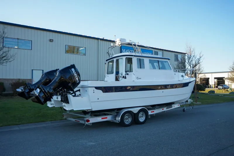Slide: The Image of 2025 C-Dory 25' Tomcat Catamaran on trailer outside industrial building. - 3