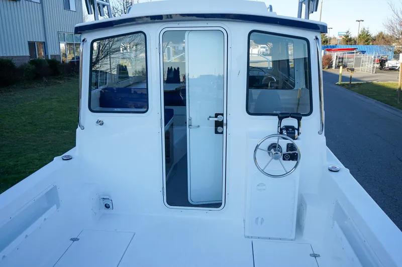 Slide: The Image of 2025 C-Dory 25' Tomcat Catamaran, rear view with steering wheel and cabin entrance. - 5