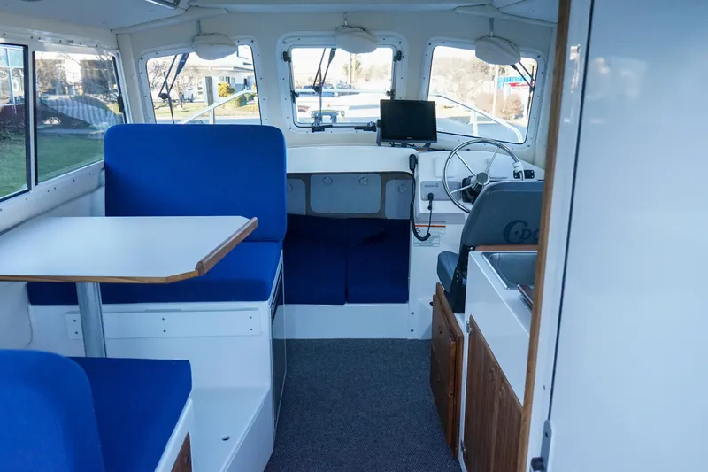 Slide: The Image of Interior of 2025 C-Dory 25' Tomcat Catamaran with blue seating and navigation equipment. - 8