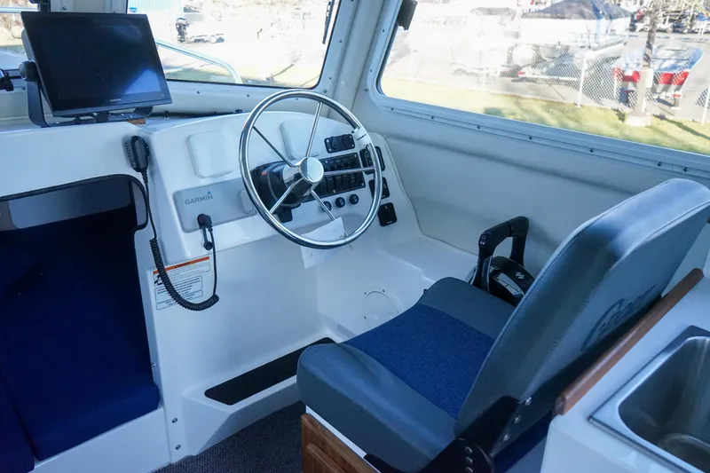 Slide: The Image of 2025 C-Dory 25' Tomcat Catamaran helm with steering wheel and navigation equipment. - 9