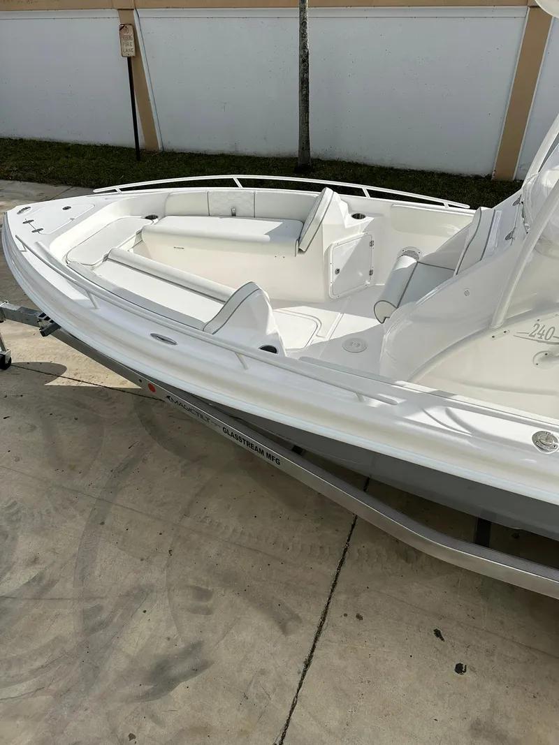 Slide: The Image of 2025 Glasstream 240 CCX boat, sleek white design, docked on concrete surface. - 7