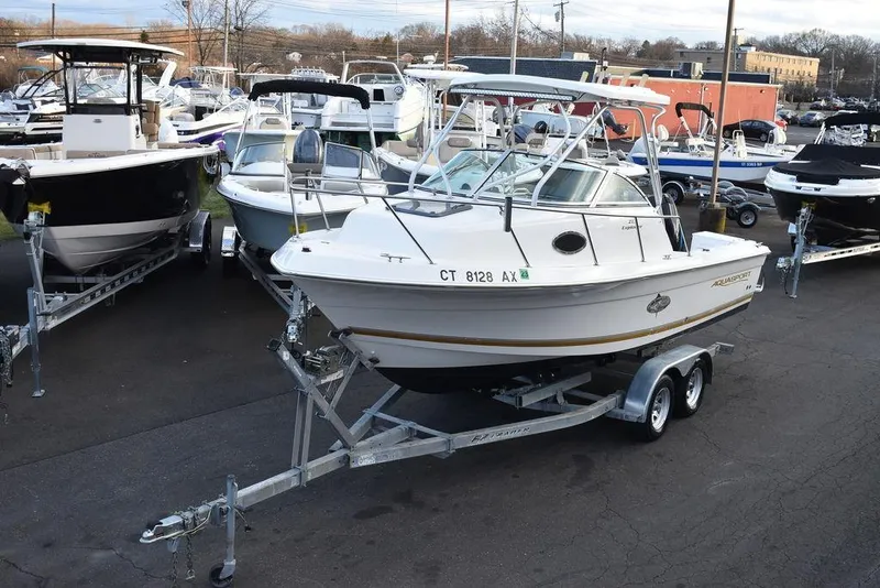 Slide: The Image of 2001 Aquasport 215 Explorer Walk-around boat on trailer, surrounded by other boats. - 3