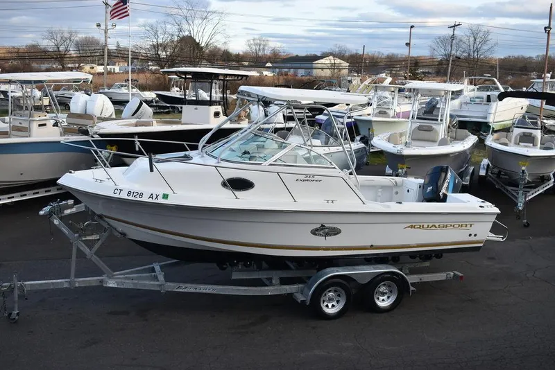 Slide: The Image of 2001 Aquasport 215 Explorer Walk-around boat on trailer, surrounded by other boats. - 5