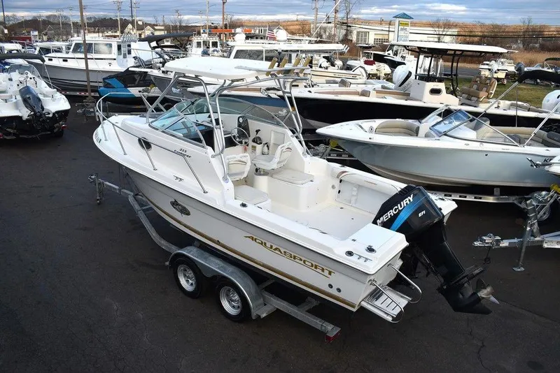 Slide: The Image of 2001 Aquasport 215 Explorer Walk-around boat on trailer, surrounded by other boats. - 7