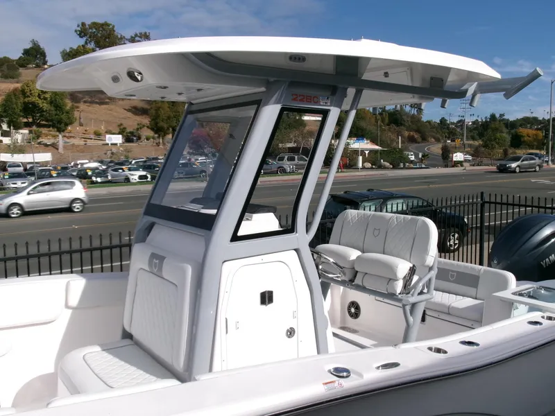 Slide: The Image of 2025 Sea Fox 228 Commander boat with T-top and seating, parked near a road. - 29