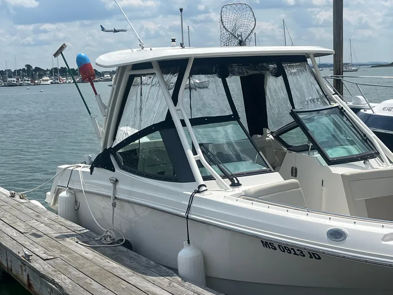 Slide: The Image of 2023 Boston Whaler 240 Vantage docked at a marina with a scenic background. - 2