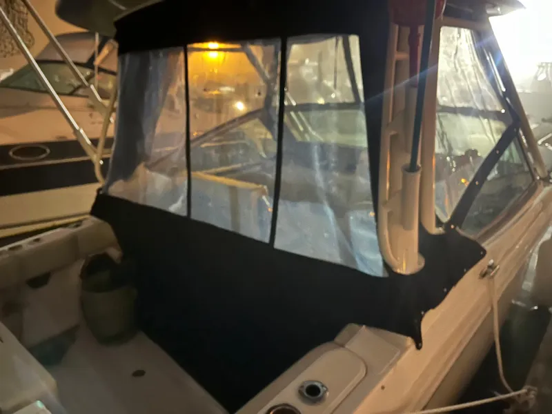 Slide: The Image of 2023 Boston Whaler 240 Vantage boat with protective cover in a dimly lit marina. - 7